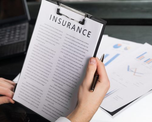 man reads insurance agreement. men's hands in white shirt with fountain pen and an insurance sheet on black table. concept of protection in modern world